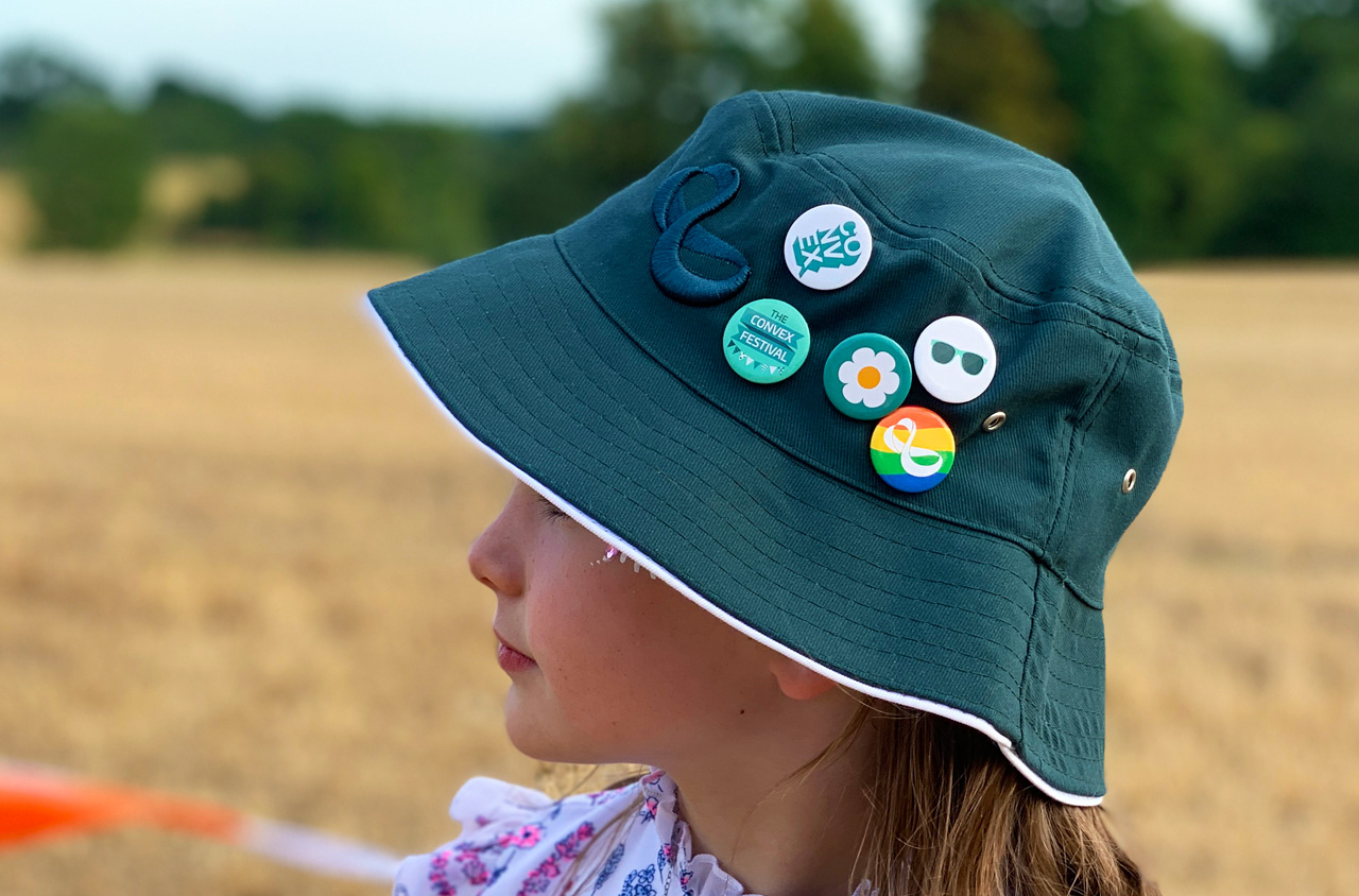 Child wearing a bucket hat with badges pinned on