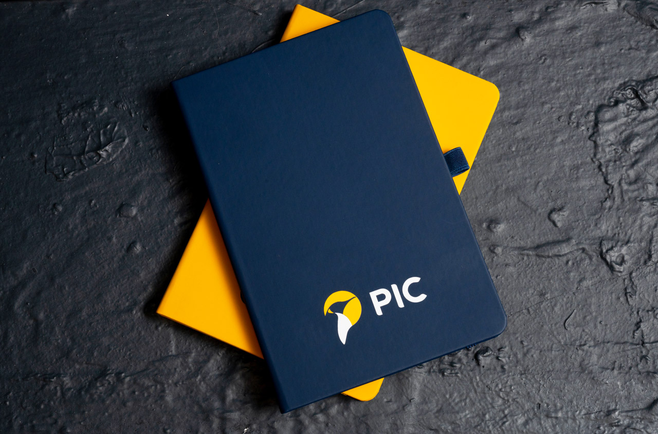 photo of two branded notebooks with the PIC logo on the front